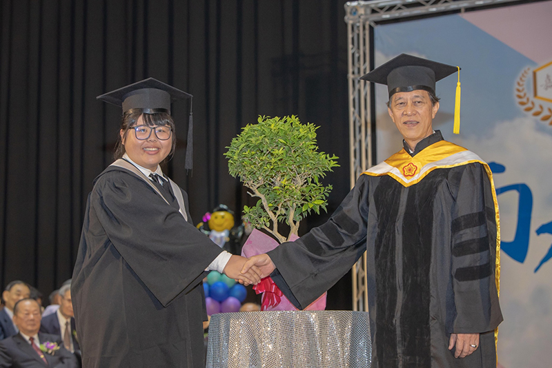 食品系畢業生王儀婷同學(左)將新生入學時的樹木回贈母校，象徵「十年樹木，百年樹人」(攝影社謝慶煌拍攝)