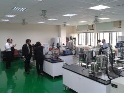 Visitors from a Japanese agricultural university inspect the Cosmetics Mass Production teaching facilities in Room B506.