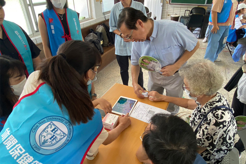 休閒系林常江老師協同學生詢問長輩身體問題並記錄，後續進行穴位按摩服務