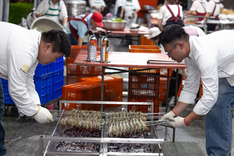 餐旅系同學黃至緯(左)及協助辦桌菜烤大蝦
