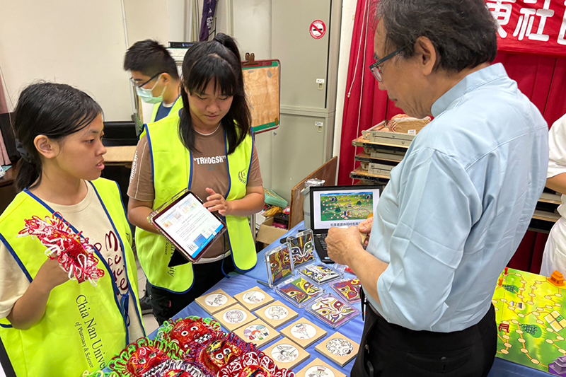 嘉藥學生透過平板向長輩介紹結合西港在地特色的實體文創品