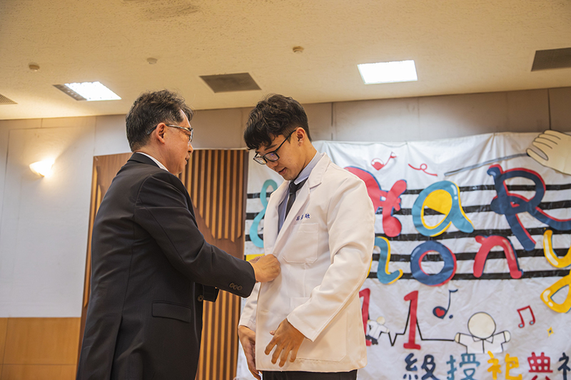 嘉藥校長張翊峰(左)為藥學系學會會長林彥融穿上白袍，象徵傳承藥師的專業使命