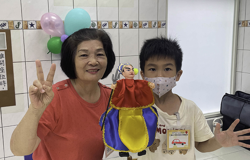 阿嬤帶著幼兒一起玩手掌布袋戲